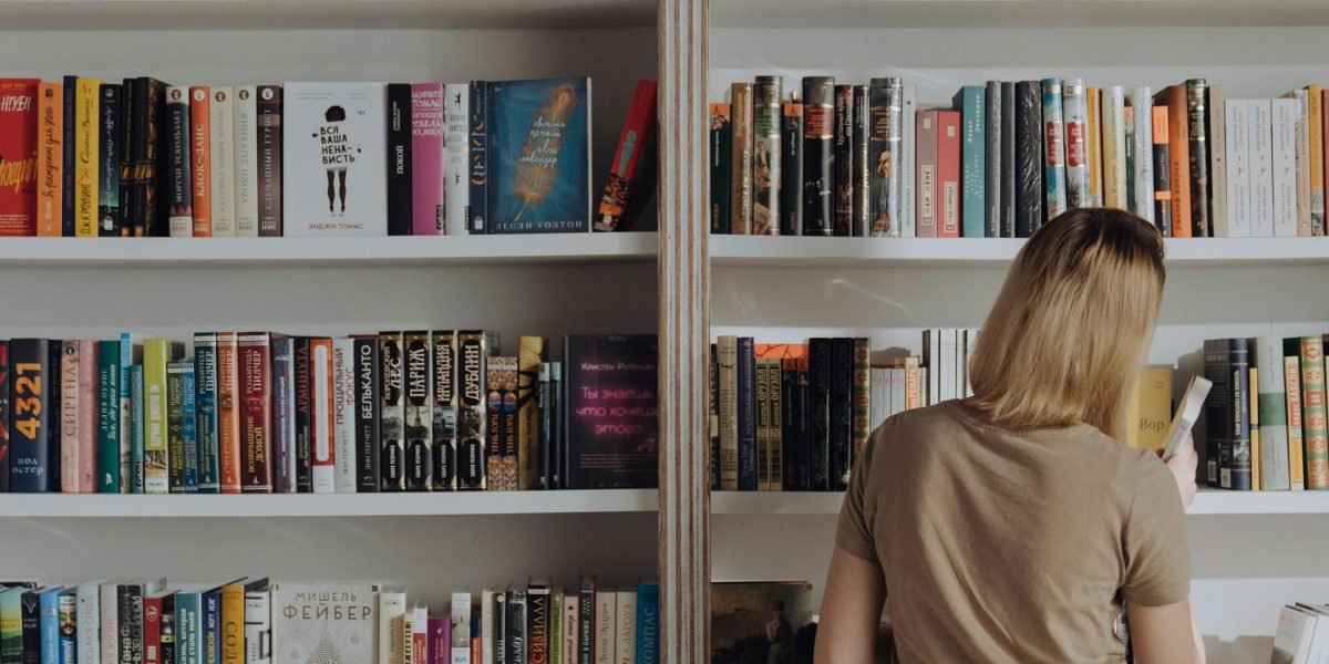 A person thoughtfully browsing through a selection of books, searching for their next captivating read.