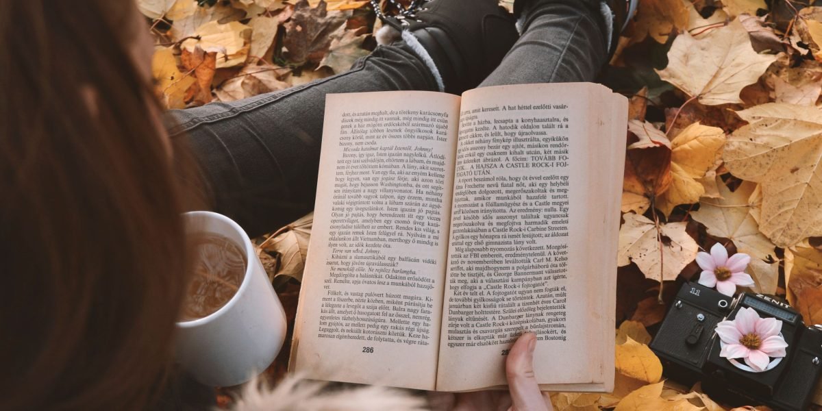 A comforting scene of someone enjoying a book with a warm drink.