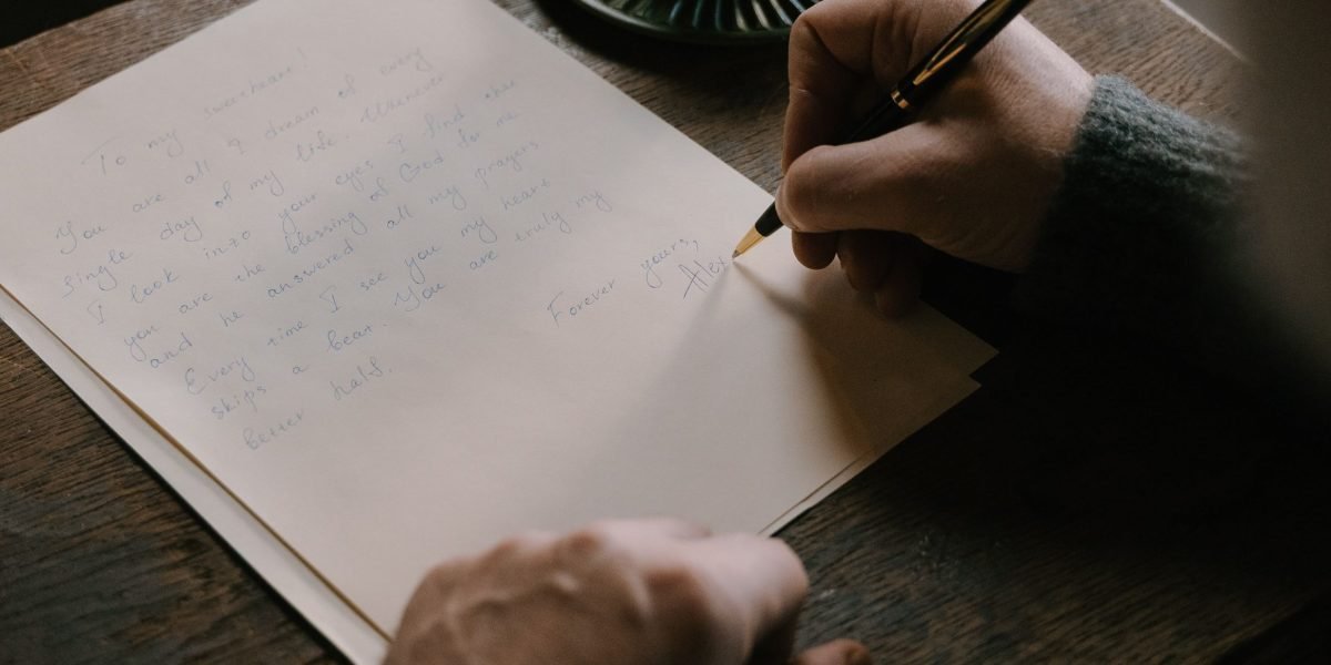 A person focused on writing in a cozy coffee shop, reflecting the quiet dedication L'Engle had to developing her craft.