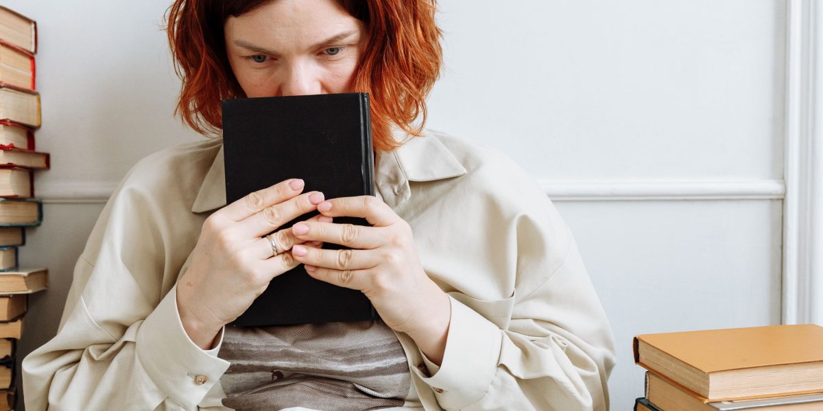 A person looking satisfied and thoughtful after finishing a thick book, reflecting on the story.